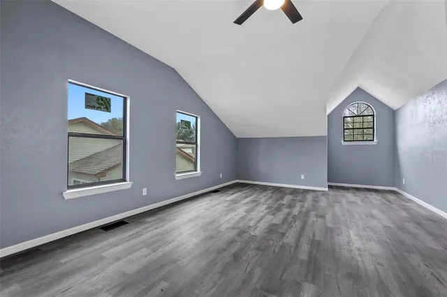 an empty room with ceiling fan and window