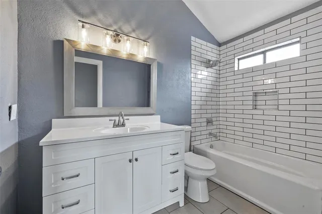 a bathroom with a granite countertop toilet a sink a mirror a bathtub and shower