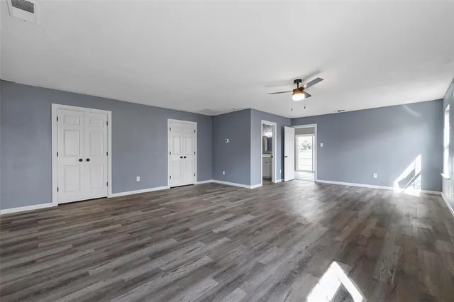 a view of an empty room with window and wooden floor