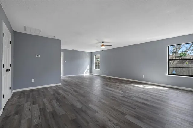 a view of an empty room with window and wooden floor