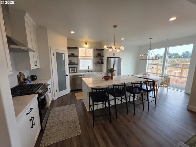 a kitchen with stainless steel appliances a dining table chairs and wooden floor