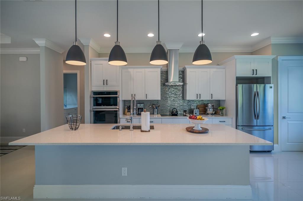 522 19th Street Northwest Naples, FL 34120 - Photo 12 of 33 a dining hall with couches a flat tv screen and a refrigerator with wooden floor