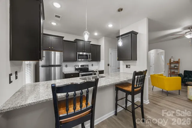 a kitchen with granite countertop kitchen island stainless steel appliances a stove a sink a refrigerator and a refrigerator