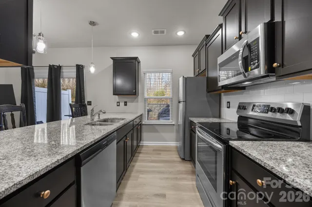 a kitchen with stainless steel appliances granite countertop wooden cabinets sink and stove
