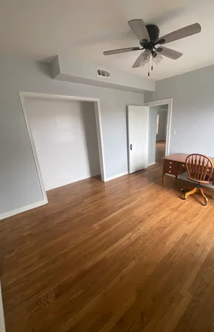 a view of a livingroom with a chandelier fan and wooden floor