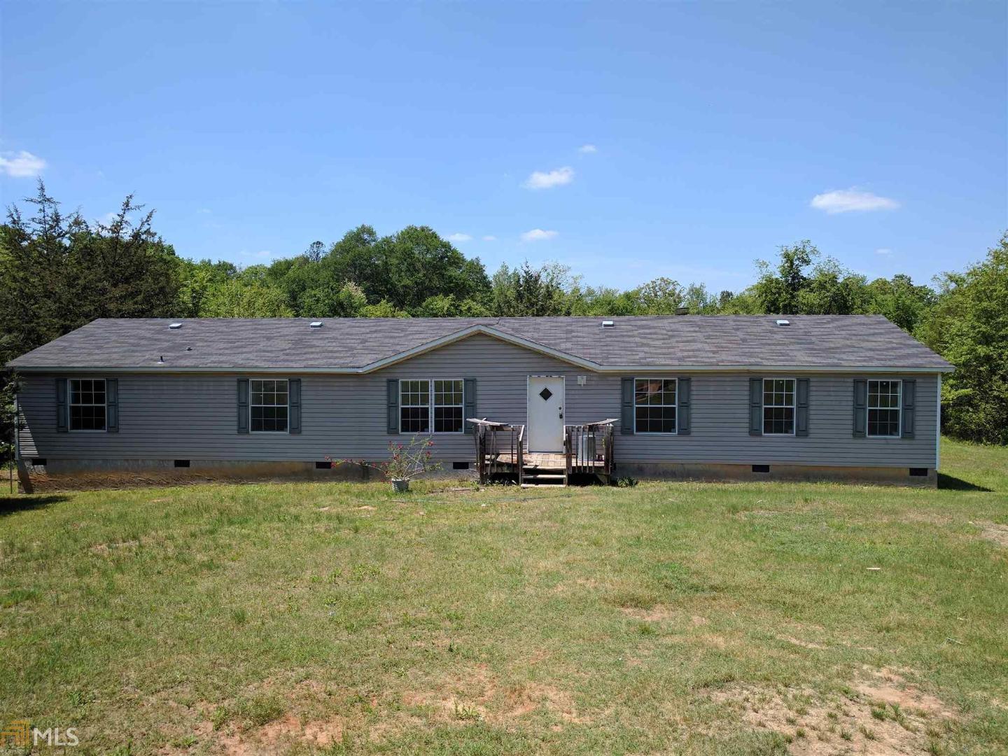 312 Alexander Road Commerce, GA 30530 - Photo 1 of 1 a house that is sitting in the grass with large trees