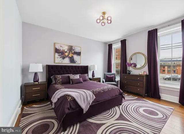 a spacious bedroom with a bed a dresser and paintings on the wall