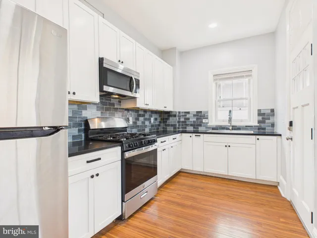 a kitchen with stainless steel appliances white cabinets and wooden floors
