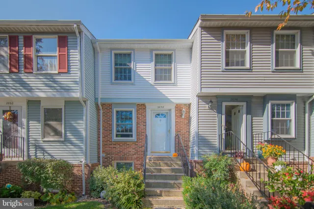 a view of a brick house with large windows and flower plants