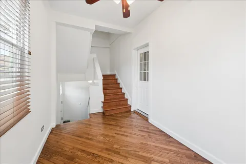 an empty room with wooden floor fan and windows