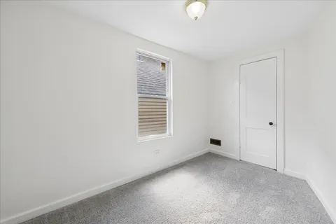 an empty room with a chandelier fan and windows