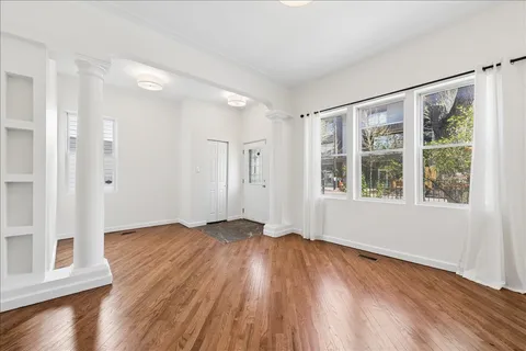 a view of an empty room with wooden floor and a window