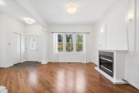 an empty room with wooden floor fireplace and windows