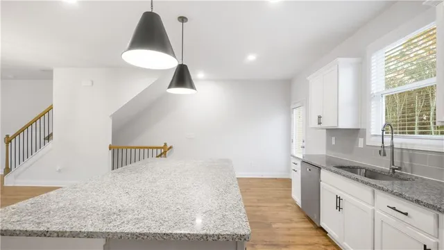 a kitchen with stainless steel appliances granite countertop a sink a stove and a wooden floors