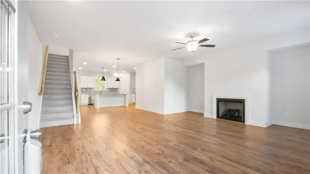 a view of an empty room with wooden floor and a ceiling fan