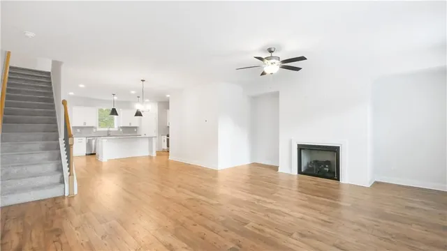 a view of an empty room with kitchen and a fireplace