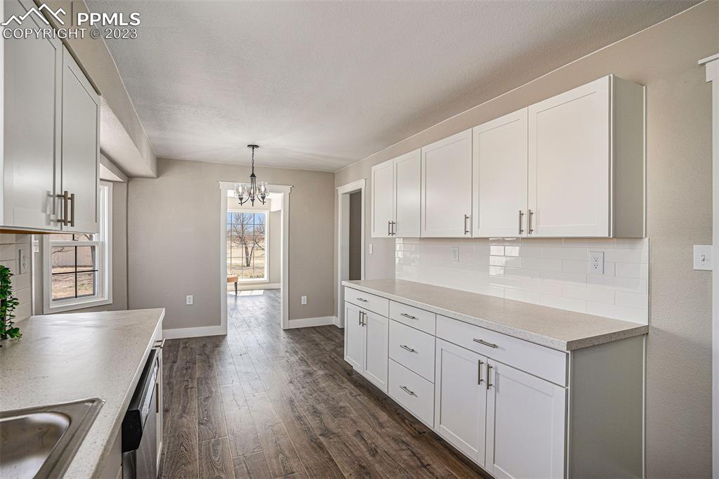 11615 Oil Well Road Calhan, CO 80808 - Photo 11 of 37 a kitchen with white cabinets and wooden floor