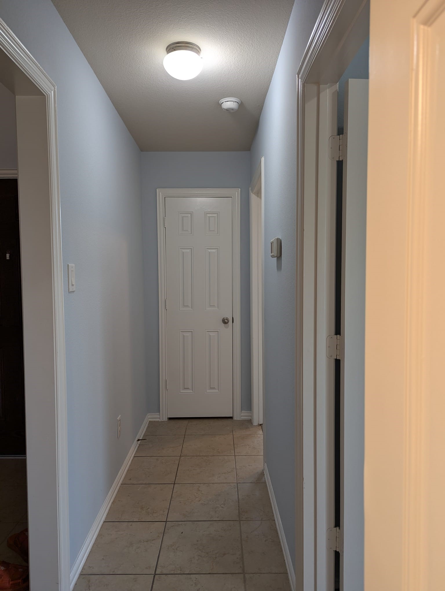 8041 Silent Deep Drive Rosenberg, TX 77469 - Photo 17 of 24 You're looking at a tidy hallway featuring light blue walls, white trim, and tile flooring. There's a white door at the end, with modern recessed lighting overhead.