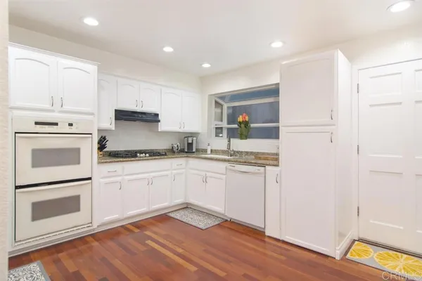 a kitchen with granite countertop white cabinets and white appliances
