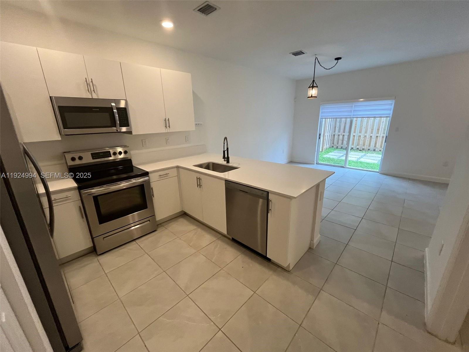 2602 Southeast 11th Street Homestead, FL 33035 - Photo 9 of 26 a kitchen with stainless steel appliances granite countertop a stove a sink and a microwave