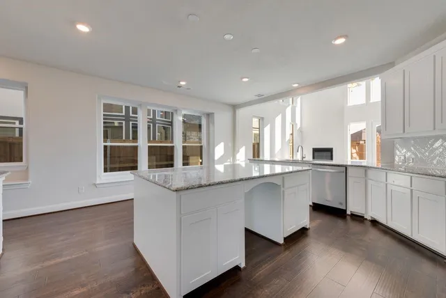 a large white kitchen with granite countertop a stove top oven a sink and dishwasher with wooden floor
