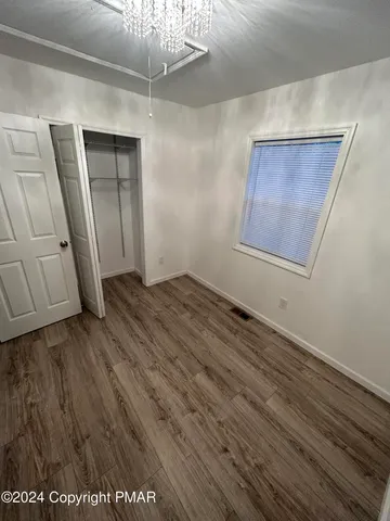 a view of an empty room with wooden floor and a ceiling fan