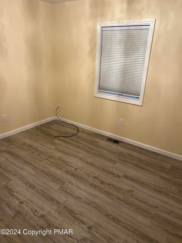 an empty room with wooden floor and mirror