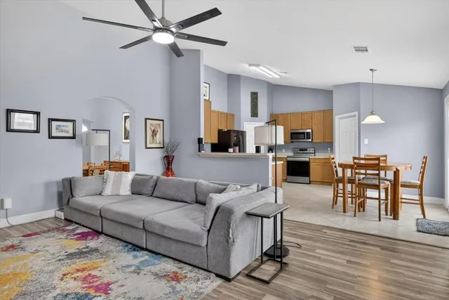 a living room with furniture kitchen view and a wooden floor