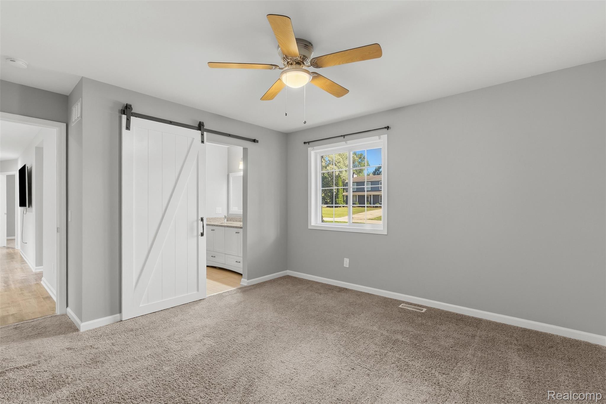 1750 Henbert Road West Bloomfield, MI 48324 - Photo 17 of 32 Barn door entry, ceiling fan with light fixture, window with exterior landscaping, light gray wall paint, and plush carpet flooring