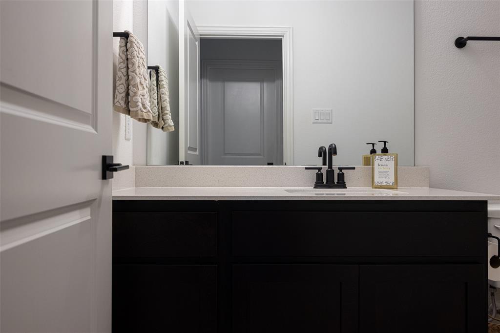 7537 Laburnam Road Dallas, TX 75228 - Photo 27 of 30 Black vanity with an integrated sink, light-toned countertop, and matte black faucet