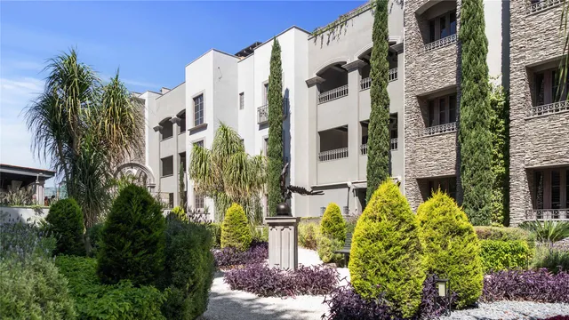 a front view of a multi story residential apartment building with yard and parking
