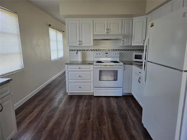 a kitchen with granite countertop white cabinets and white appliances