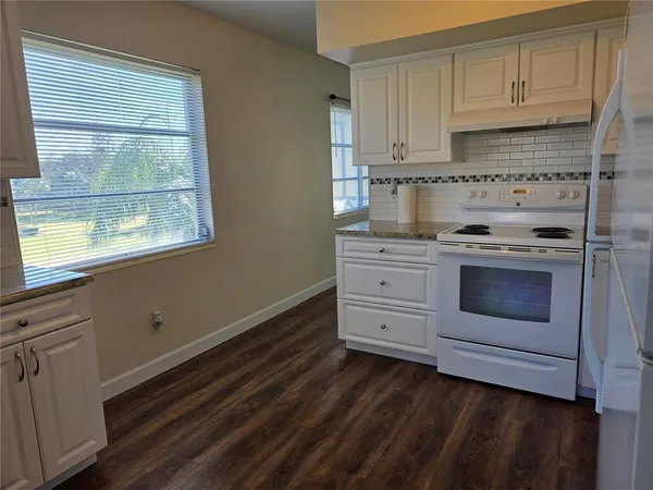 a kitchen with granite countertop white cabinets and white appliances