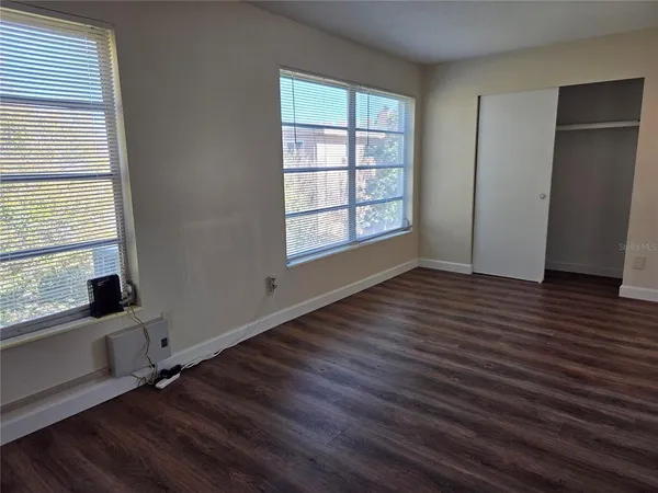 an empty room with wooden floor and windows