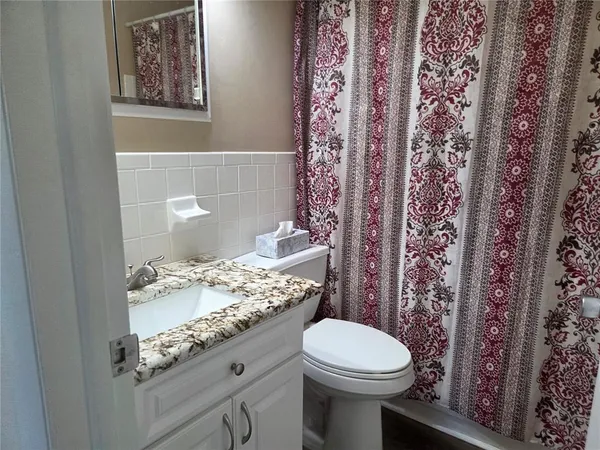 a bathroom with a granite countertop sink a toilet and a mirror