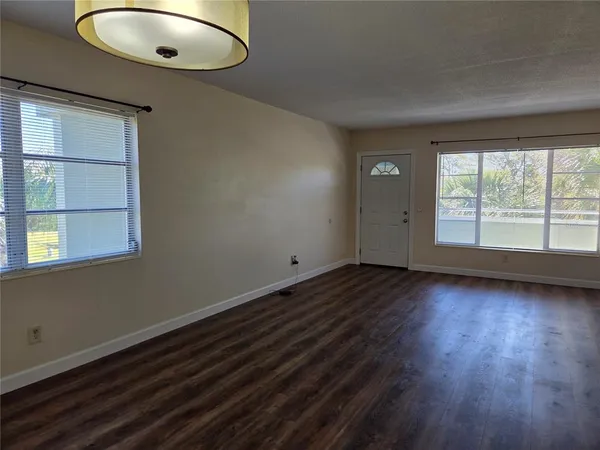 an empty room with wooden floor chandelier and windows