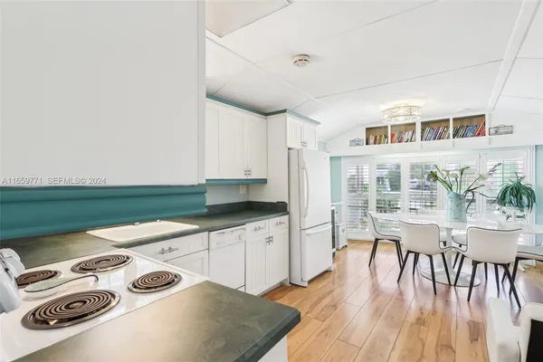 a kitchen with stainless steel appliances granite countertop a stove and white cabinets with wooden floor