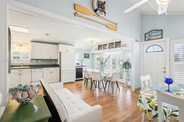 a view of a dining room with furniture one side kitchen view and wooden floor