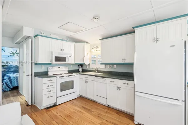 a kitchen with stainless steel appliances granite countertop a stove a sink and white cabinets