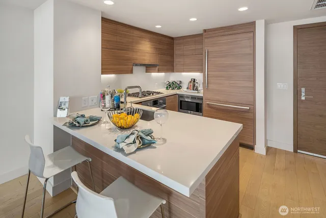 a kitchen with stainless steel appliances a white table chairs and a refrigerator