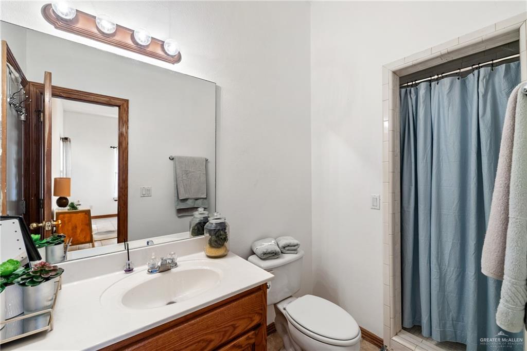 8413 North Main Street McAllen, TX 78504 - Photo 25 of 37 a bathroom with a sink a toilet a mirror and shower curtain