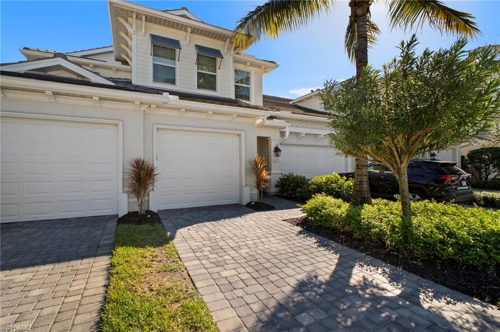 6934 Avalon Circle, Unit 405 Naples, FL 34112 - Photo 1 of 16 View of front of house featuring stucco siding, decorative driveway, and a garage