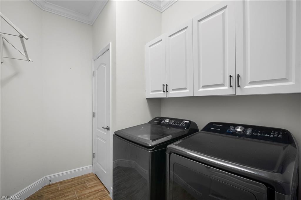6934 Avalon Circle, Unit 405 Naples, FL 34112 - Photo 13 of 16 Laundry area featuring wood finish floors, crown molding, cabinet space, and washer and clothes dryer