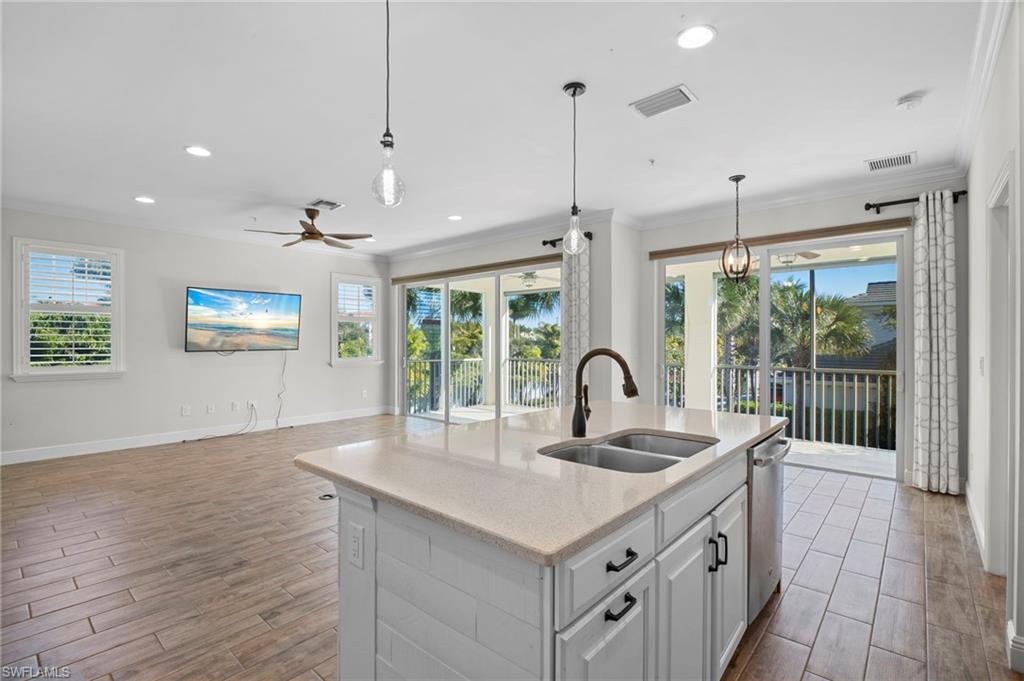 6934 Avalon Circle, Unit 405 Naples, FL 34112 - Photo 9 of 16 Kitchen featuring white cabinets, wood finish floors, light stone countertops, pendant lighting, and recessed lighting