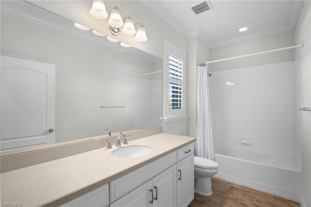6934 Avalon Circle, Unit 405 Naples, FL 34112 - Photo 10 of 16 Full bathroom featuring vanity, shower / bath combination with curtain, dark wood-style flooring, and crown molding