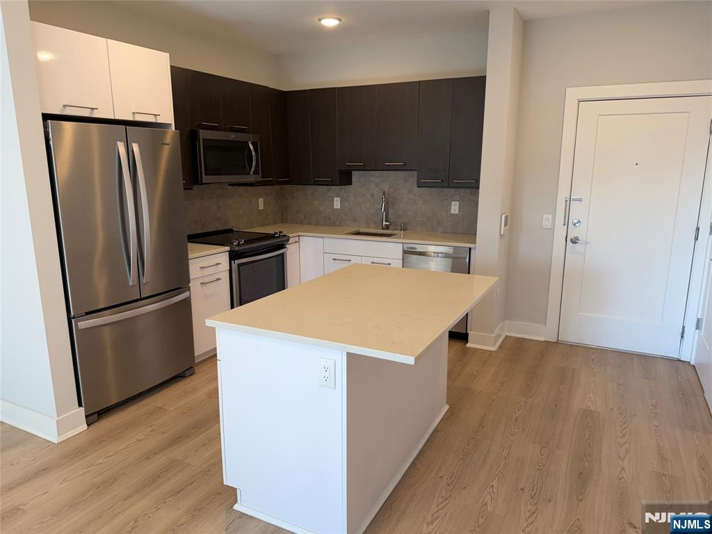2150 North Central Road, Unit 410 Fort Lee, NJ 07024 - Photo 3 of 15 a kitchen with stainless steel appliances a refrigerator a stove a sink and a center island