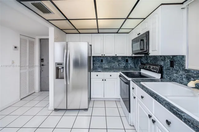 a kitchen with stainless steel appliances granite countertop a refrigerator a sink and white cabinets