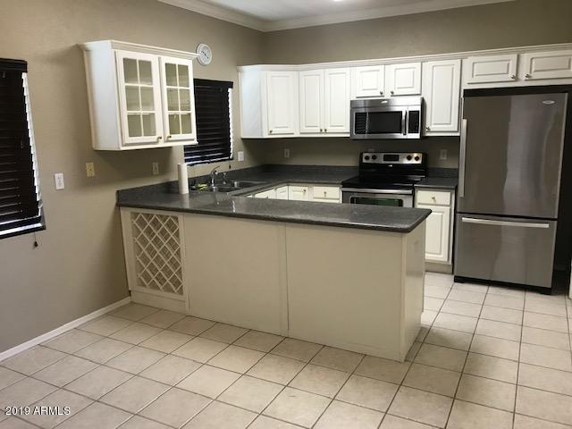 8940 West Olive Avenue, Unit 15 Peoria, AZ 85345 - Photo 2 of 9 a kitchen with stainless steel appliances granite countertop a stove a sink and a refrigerator