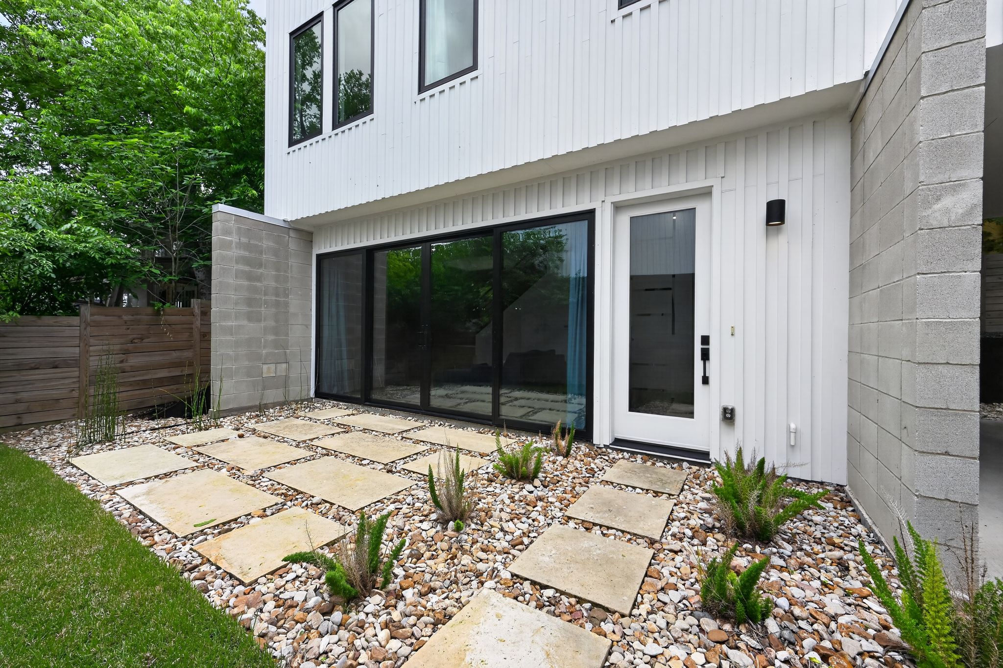 1206 Luna Street, Unit 2 Austin, TX 78721 - Photo 5 of 30 The property features a patio area with large square pavers set in a bed of decorative rocks, bordered by a well-maintained lawn
