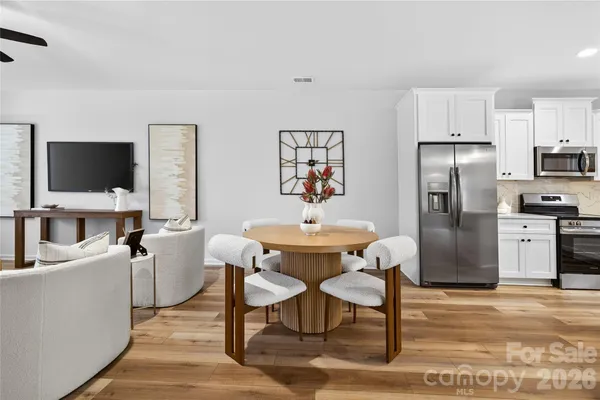 a kitchen with stainless steel appliances a refrigerator a stove a dining table and chairs